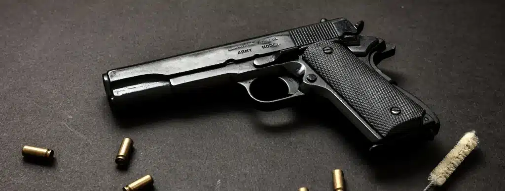 Black 1911 pistol and brass cartridge cases on a dark surface